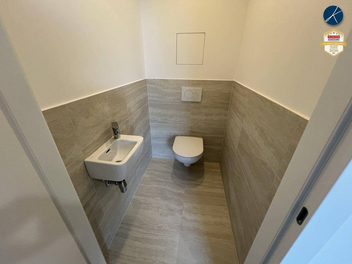 Kleines Gäste-WC mit Wand-WC und Handwaschbecken, modern gefliest.