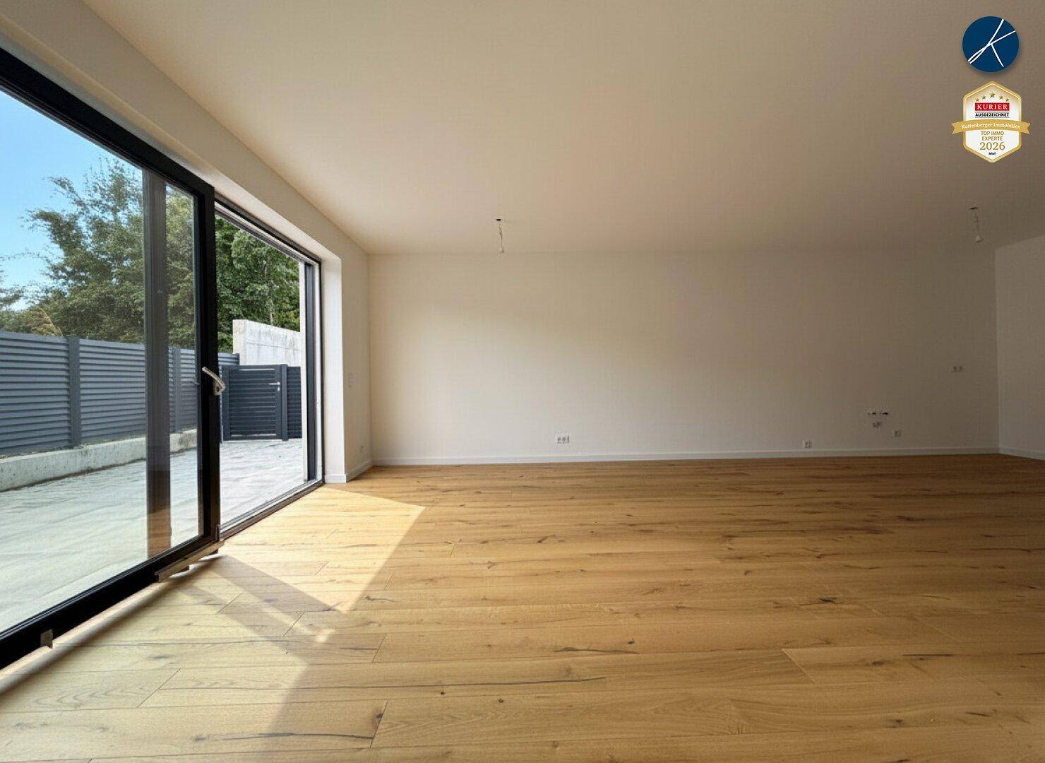 Helles Wohnzimmer mit Holzboden und großen Schiebetüren, die den Blick nach draußen freigeben.