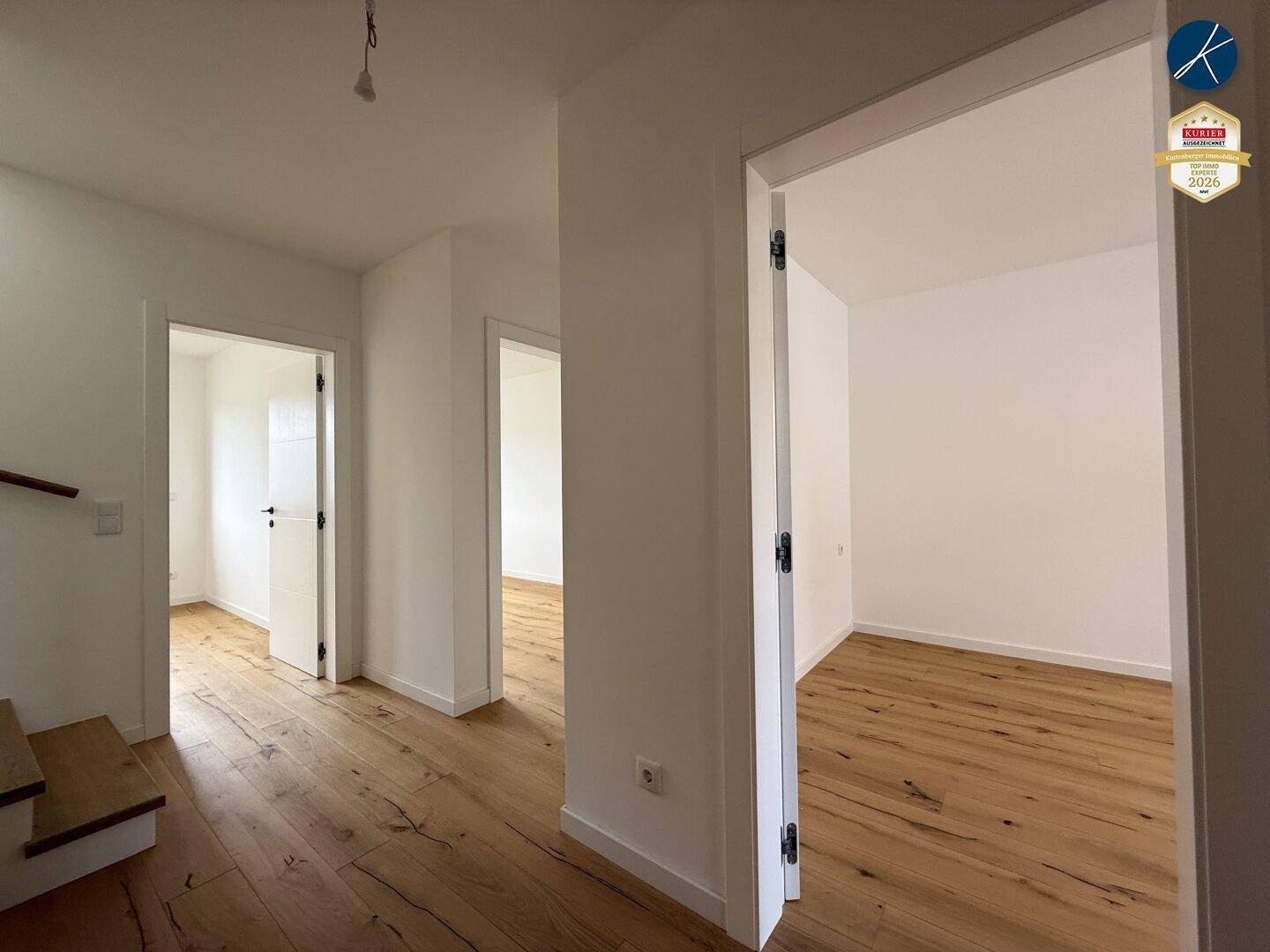 Heller Flur im Obergeschoss mit Holzboden und Zugang zu mehreren Zimmern.