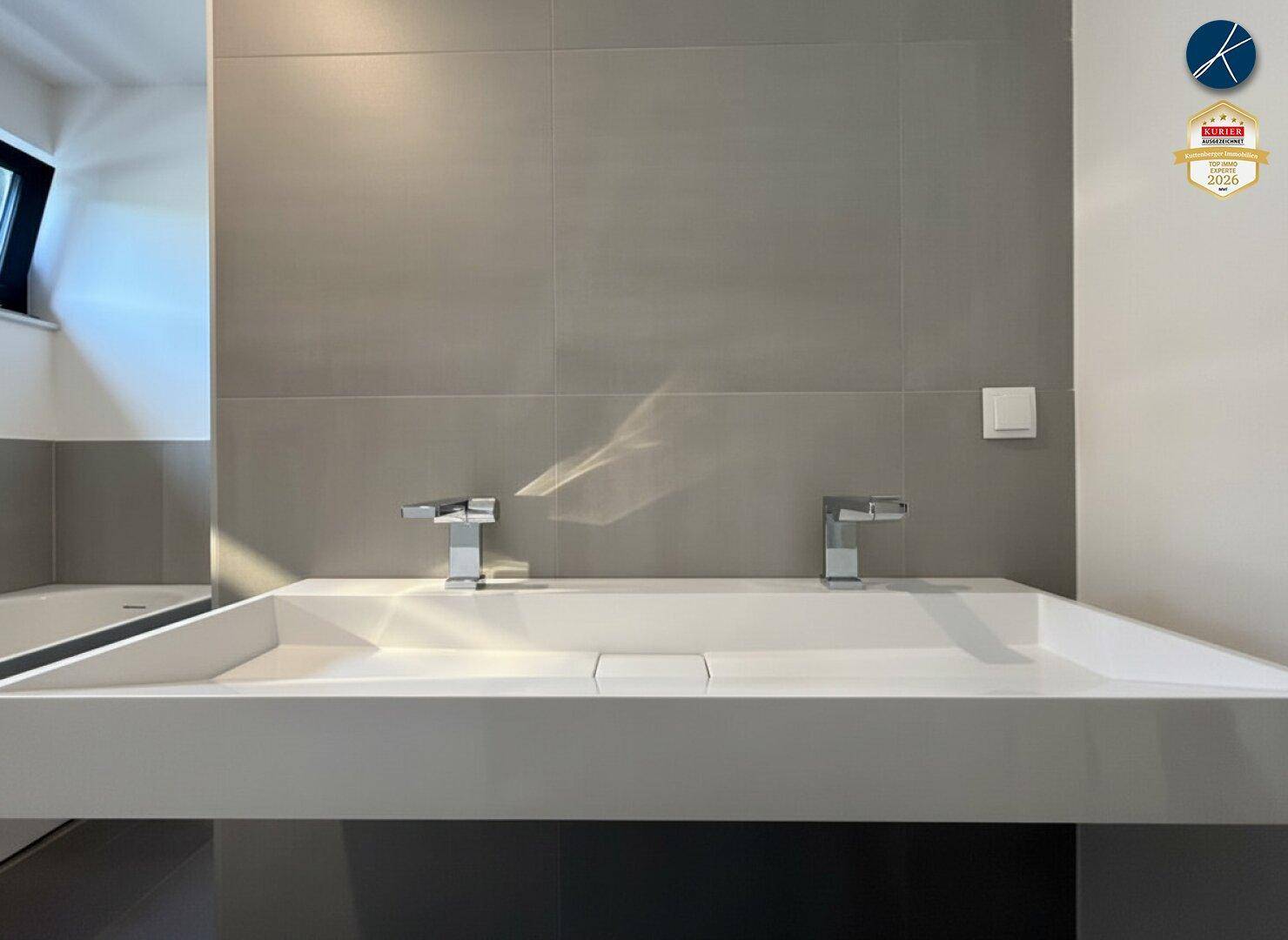 Modernes Badezimmer mit Doppelwaschbecken und grauen Fliesen, das eine schlichte Ästhetik aufweist.