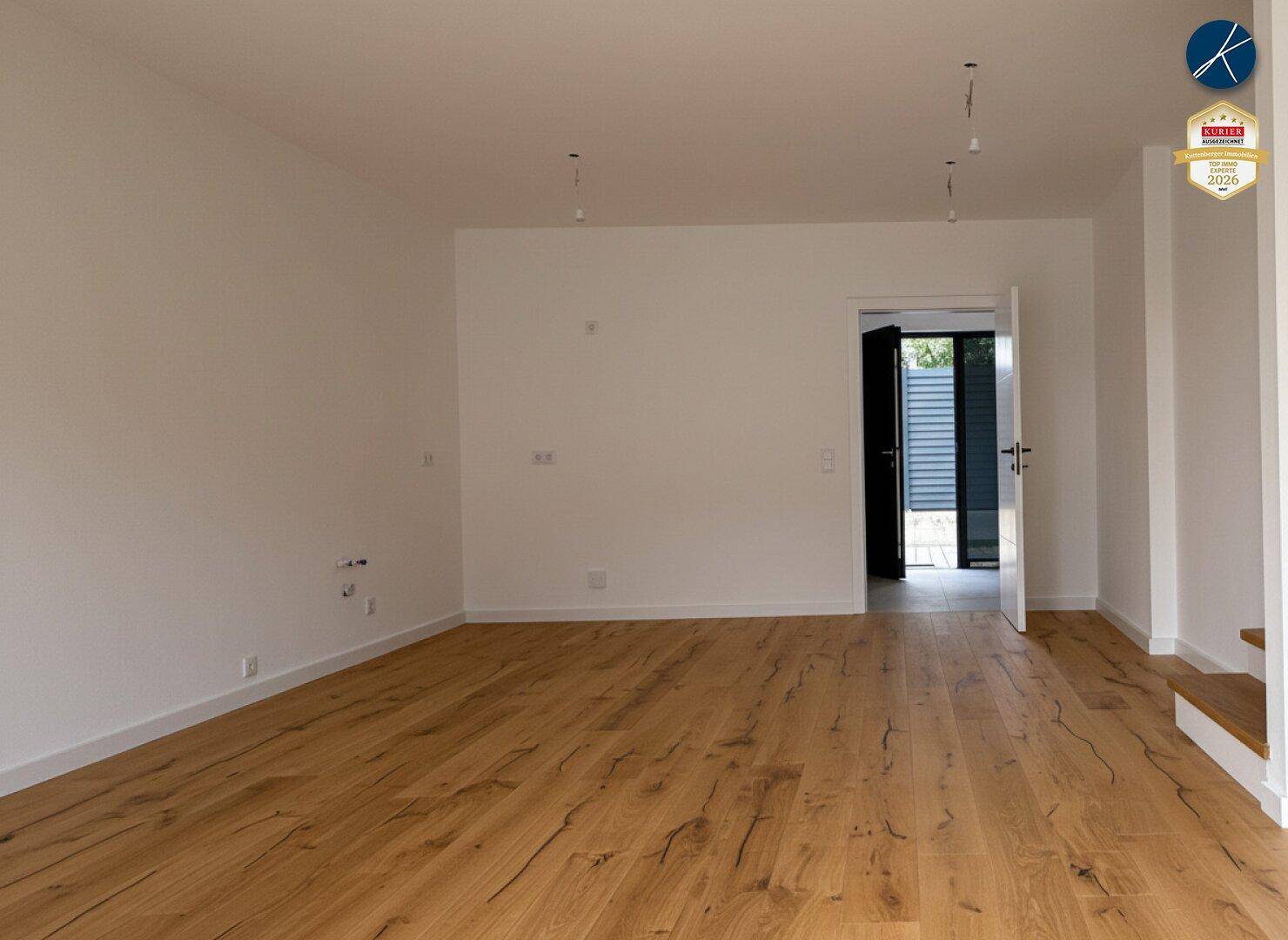 Geräumiges, leeres Wohnzimmer mit hellem Holzplankenboden und weiß gestrichenen Wänden, bereit zum Einzug.