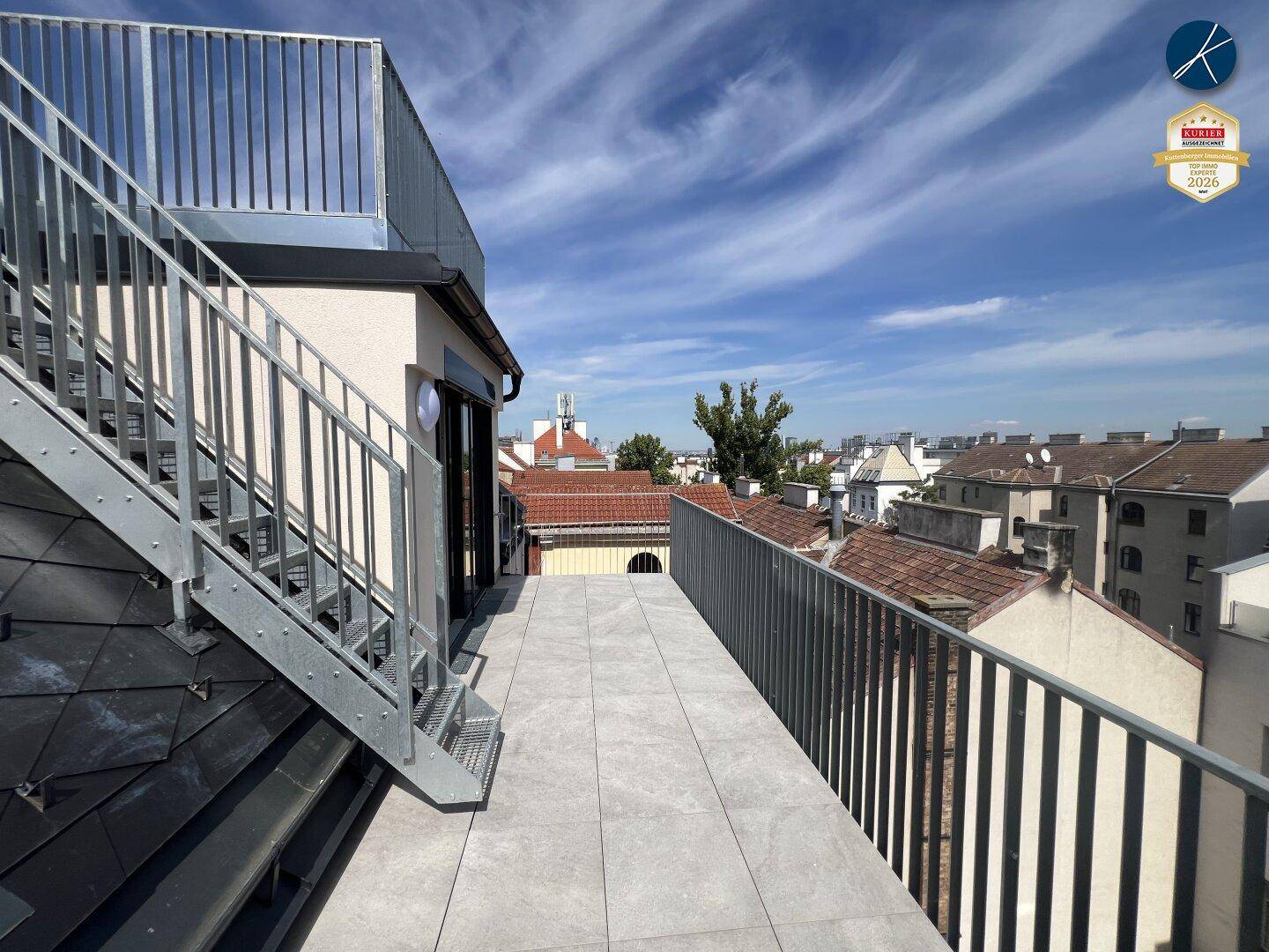 Sonniger Terrassenbereich mit Fliesenboden und Metallgeländer, bietet einen schönen Stadtblick.