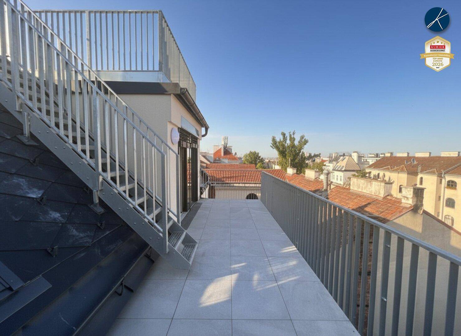 Außenbereich mit gefliester Terrasse, Metallgeländer und Treppe zu einer weiteren Ebene.