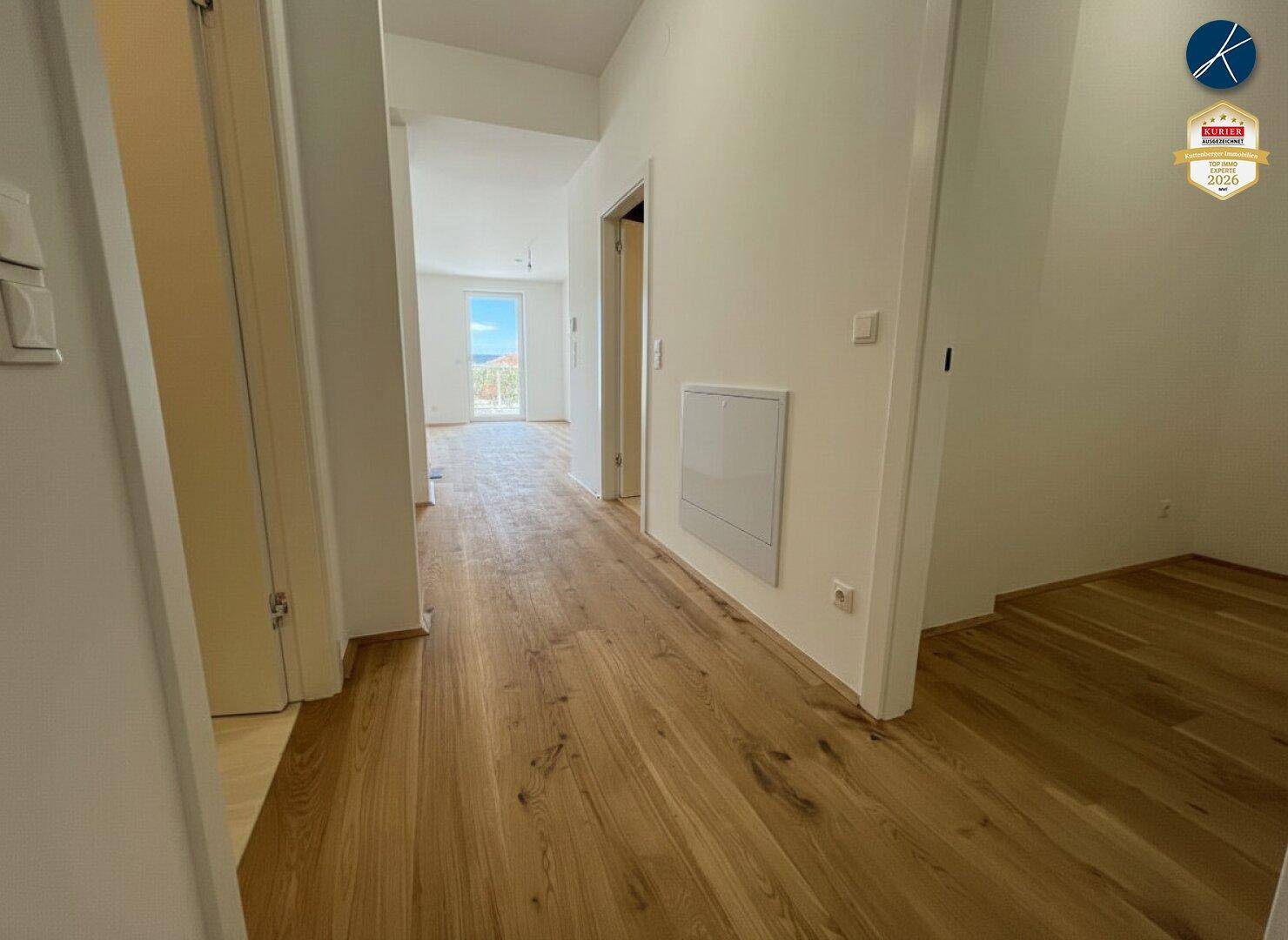 Heller Flur mit Holzboden, der zu weiteren Räumen und einem offenen Bereich führt.