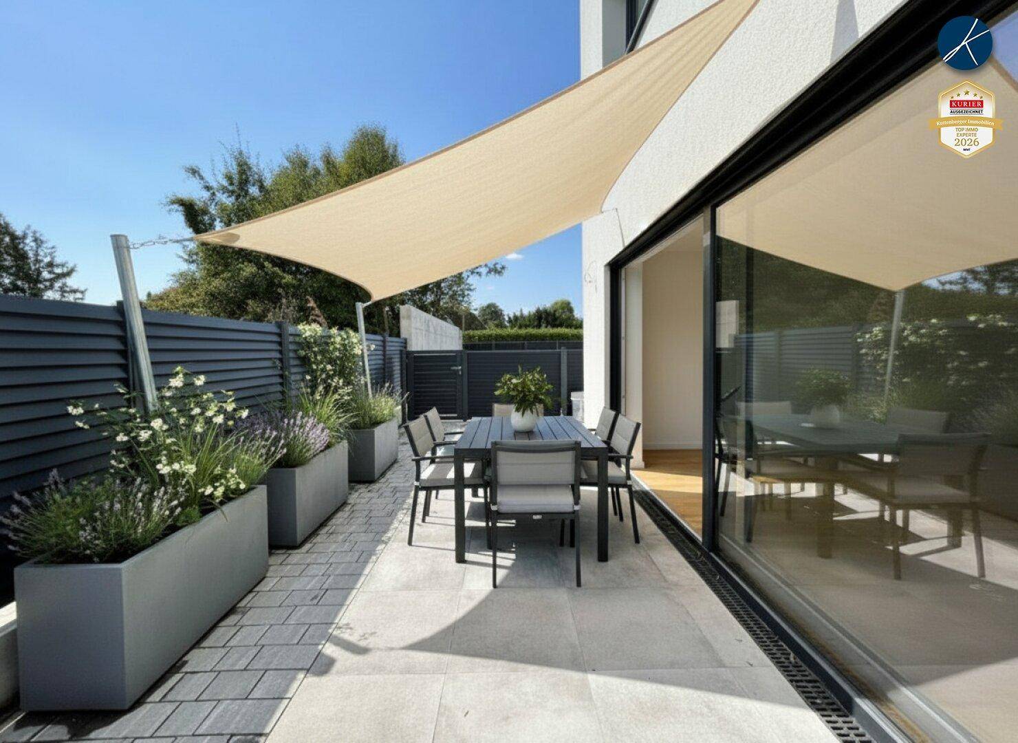 Möblierte Terrasse mit Esstisch, Sonnensegel und dekorativen Pflanzen, ideal für Mahlzeiten im Freien.