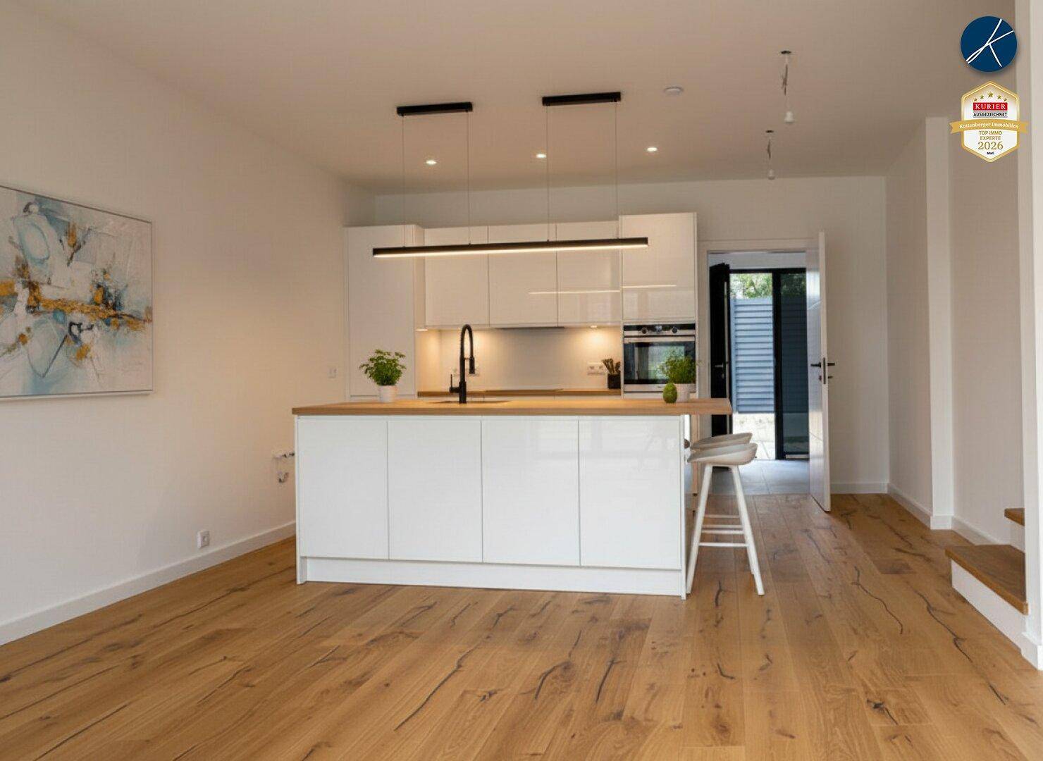 Moderne, offene Küche mit weißer Hochglanzinsel, Holzarbeitsplatte und Holzboden.