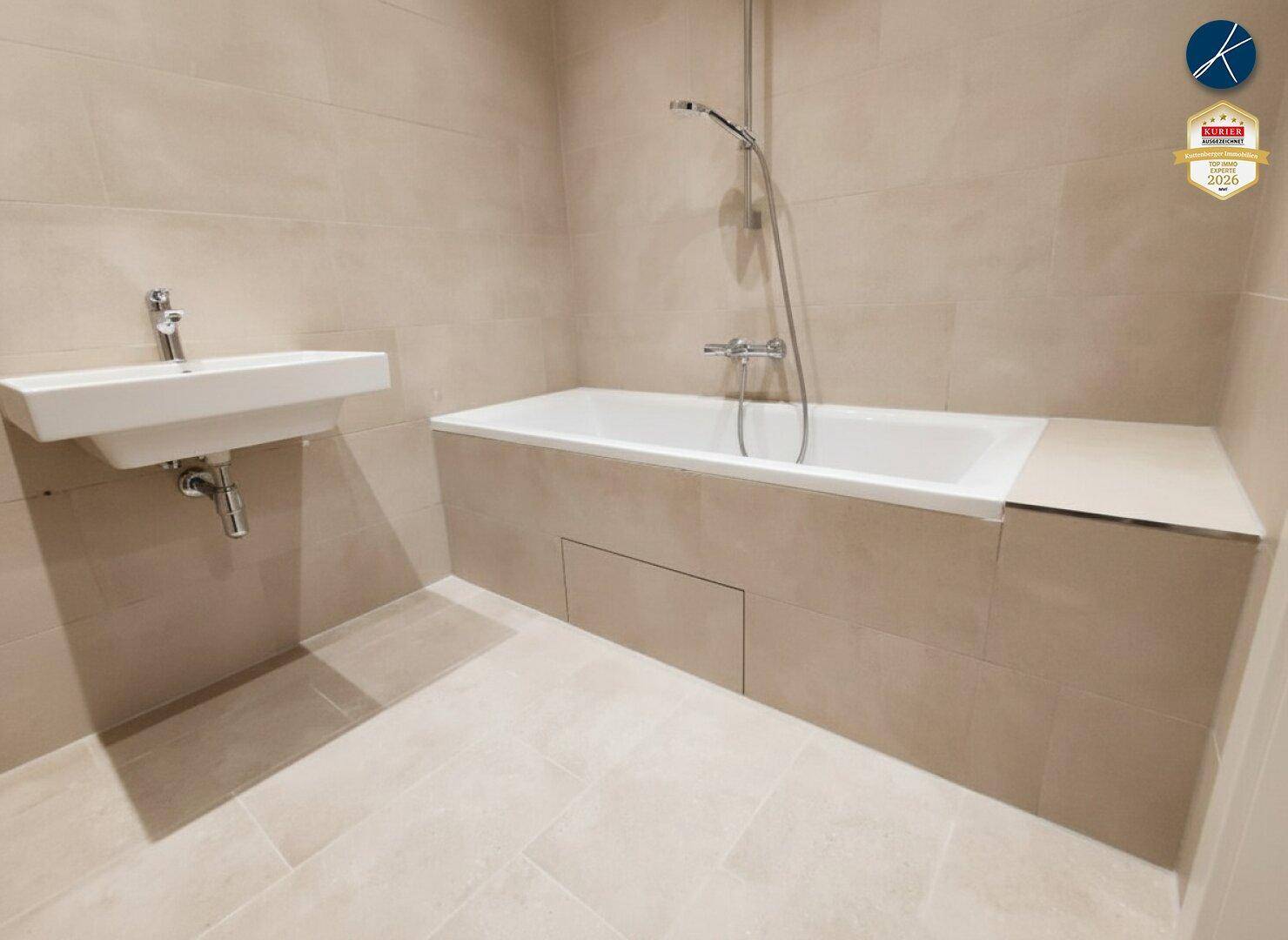 Modernes Badezimmer mit beigefarbenen Fliesen, Badewanne und einem schwebenden Waschbecken.