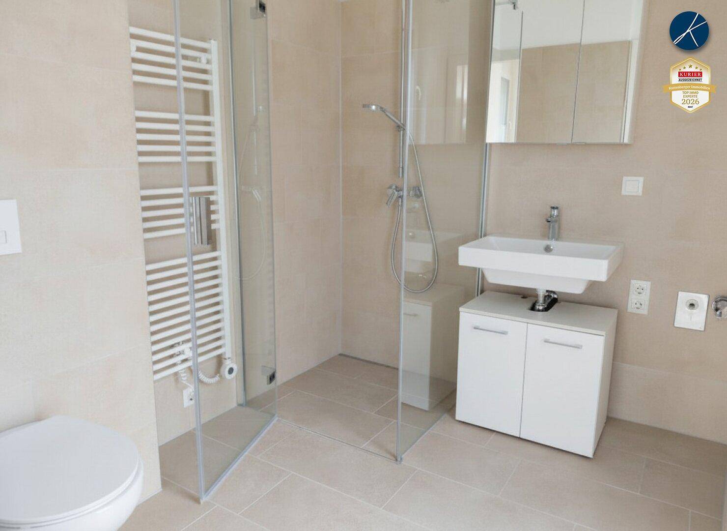 Modernes Badezimmer mit beigefarbenen Fliesen, ebenerdiger Dusche und Handtuchheizkörper.