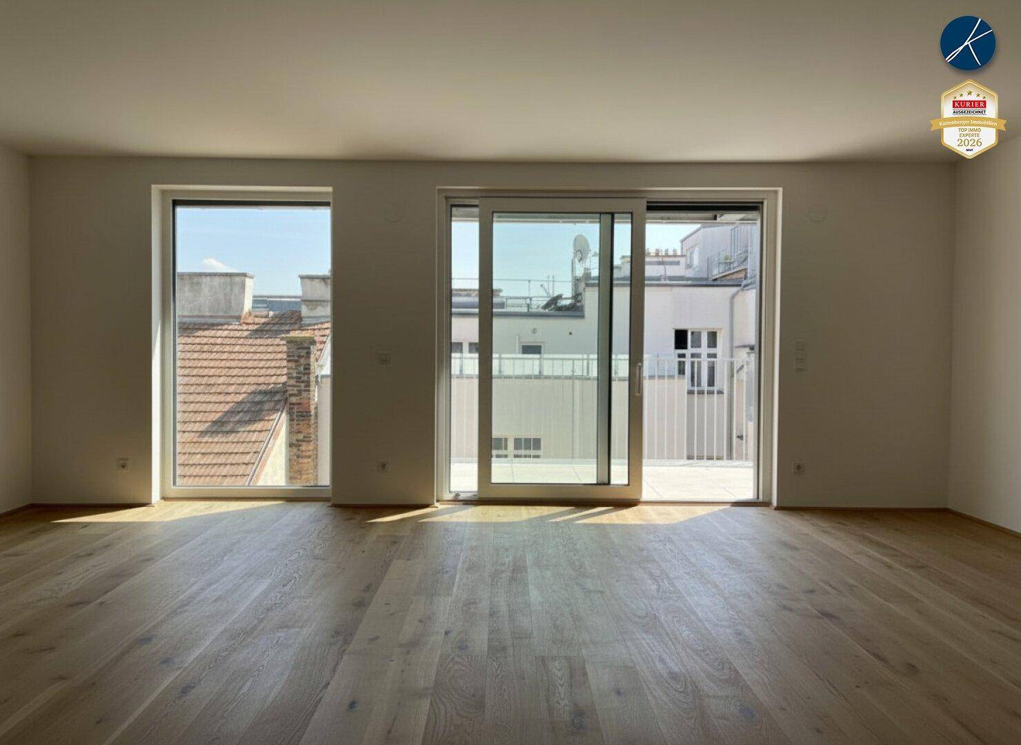 Lichtdurchfluteter Wohnraum mit Holzboden und Blick auf die umliegenden Dächer.
