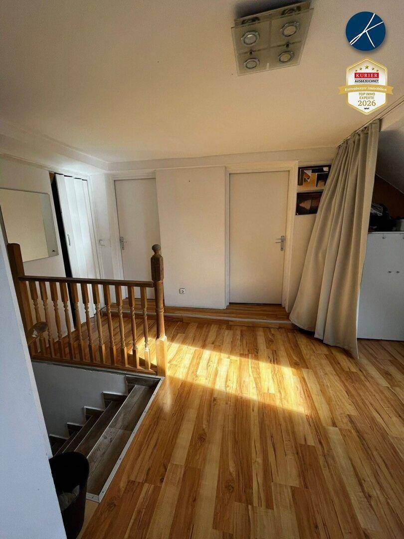 Heller Flur im Dachgeschoss mit Holztreppe und Holzboden.
