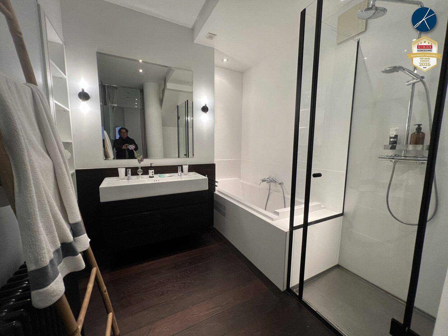 Modernes Badezimmer mit Dusche, Badewanne, Einzelwaschbecken und dunklem Holzboden.