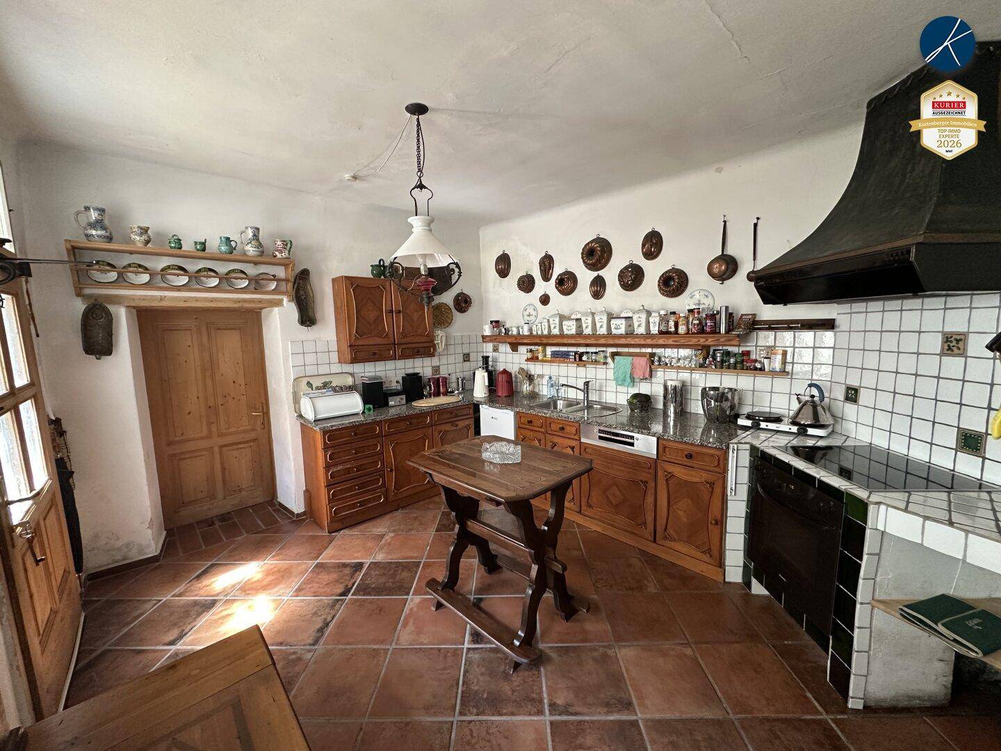 Rustikale Küche mit Holzeinbauten, Terrakottafliesen und traditionellen Dekorationen an den Wänden.