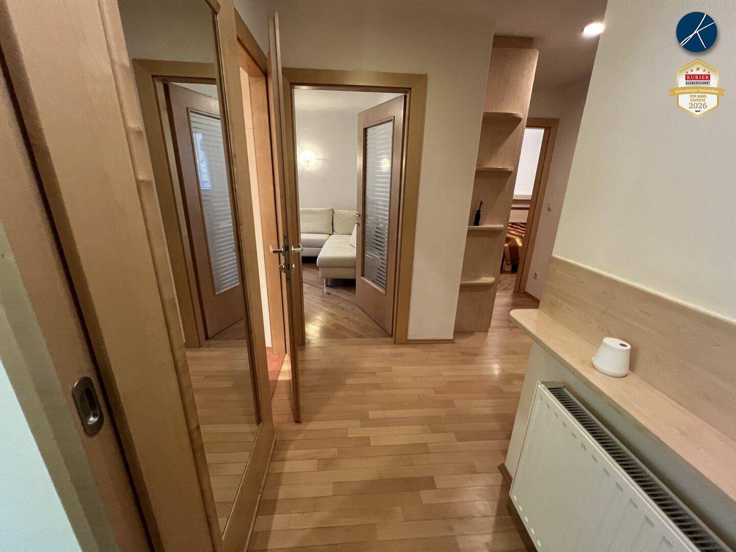 Heller Flur mit Holzparkettboden, Spiegeltüren und Zugang zu weiteren Räumen.