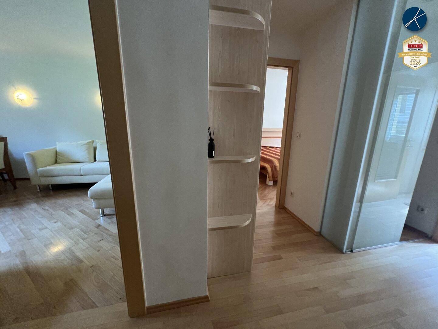 Heller Flur mit Holzparkettboden und dekorativem Regal, der zu verschiedenen Zimmern führt.