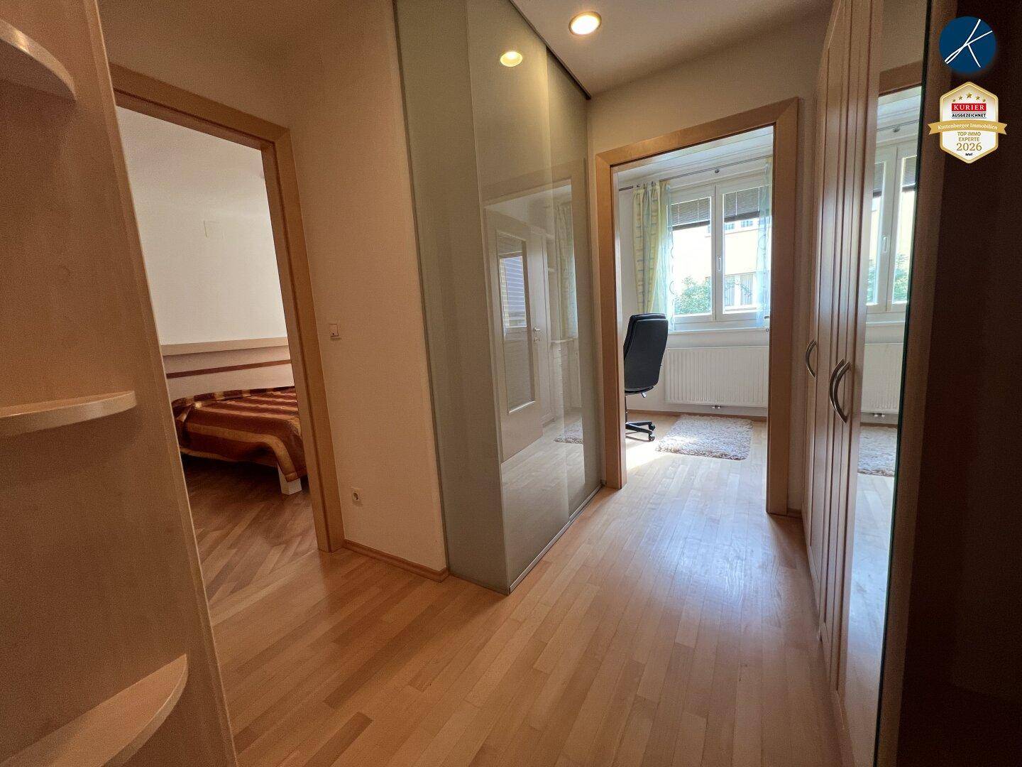 Flur mit Holzparkettboden und Spiegelschränken, der zu einem Schlafzimmer und Büro führt.