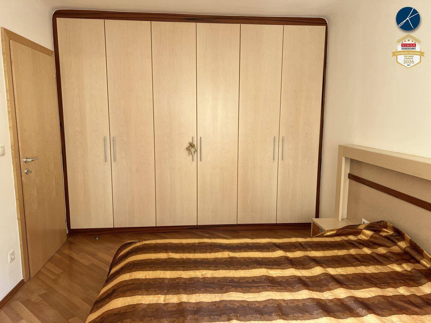 Schlafzimmer mit großem Einbauschrank und Holzboden, bietet viel Stauraum.