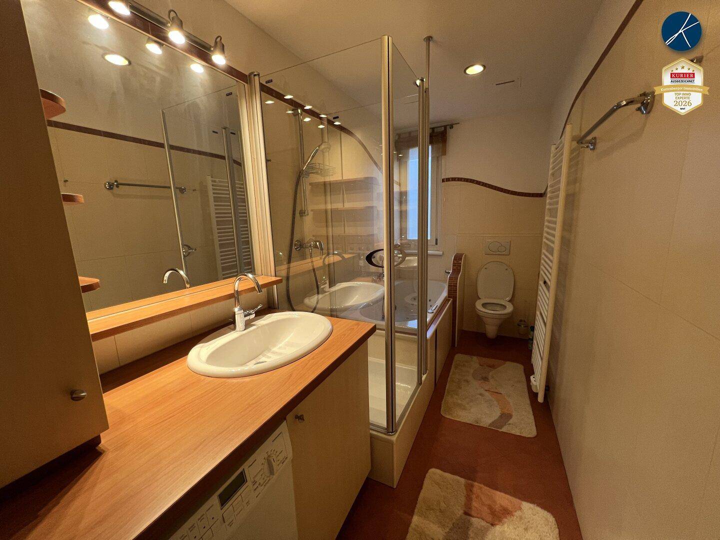 Geräumiges Badezimmer mit Badewanne, Dusche, Einzelwaschbecken und Holzwaschtisch.