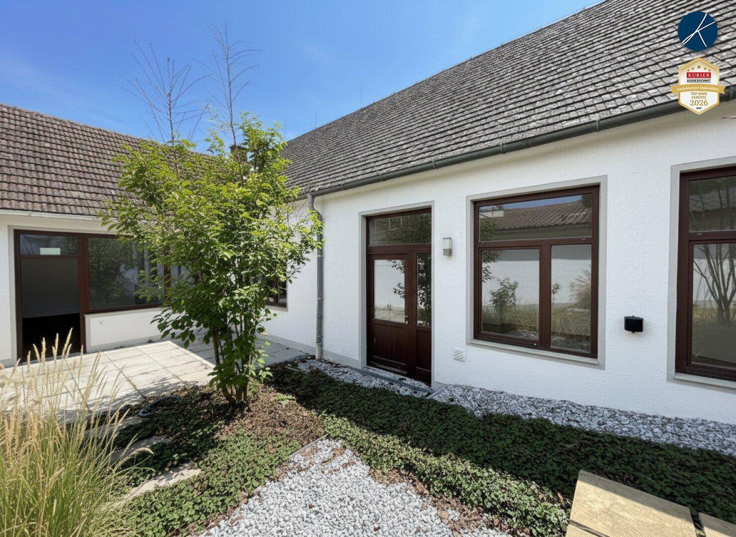 Kleiner, gepflegter Gartenbereich mit Kies und niedriger Bepflanzung neben dem Gebäude.