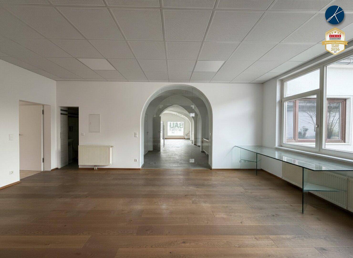Offener Bereich mit Holzboden und Bögen, der zu weiteren Räumen mit Gewölbedecken führt.