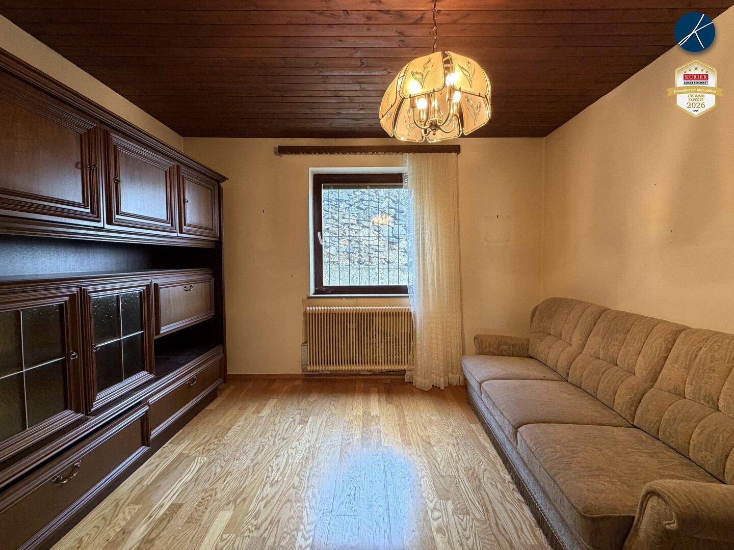 Wohnraum mit Parkettboden, Holzdecke, großem Schrank und Sofa in traditionellem Stil.