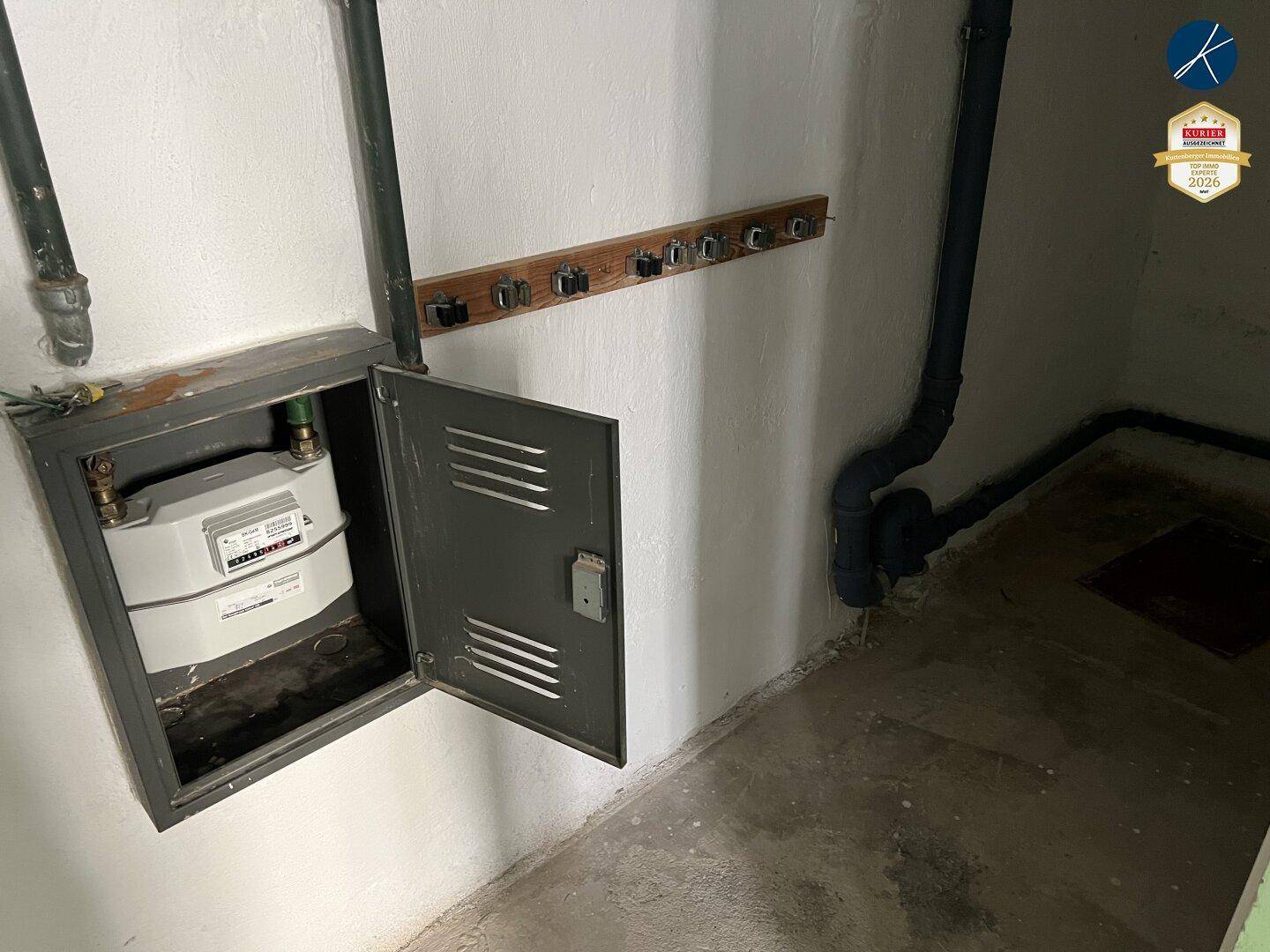 Technikraum mit Gaszähler und sichtbaren Rohrleitungen an der Wand.