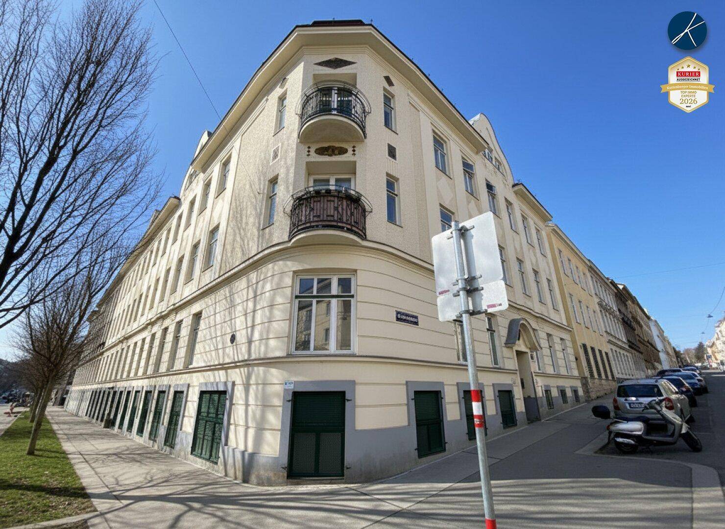 Weitläufige Ansicht des Eckgebäudes mit klassischer Architektur und umliegender Straße.