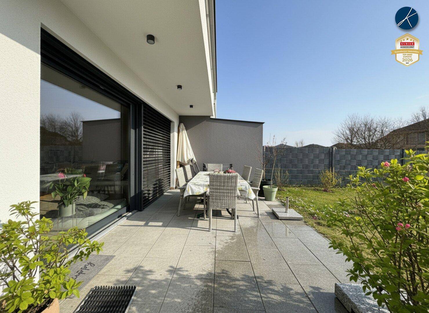 Gepflasterte Terrasse mit Esstisch und Stühlen, ideal für Mahlzeiten im Freien.