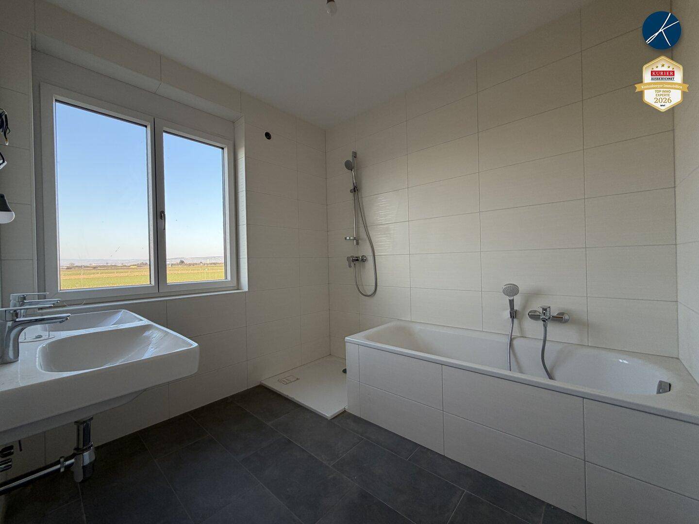 Modernes Badezimmer mit Badewanne, Dusche, Einzelwaschbecken und Fenster.