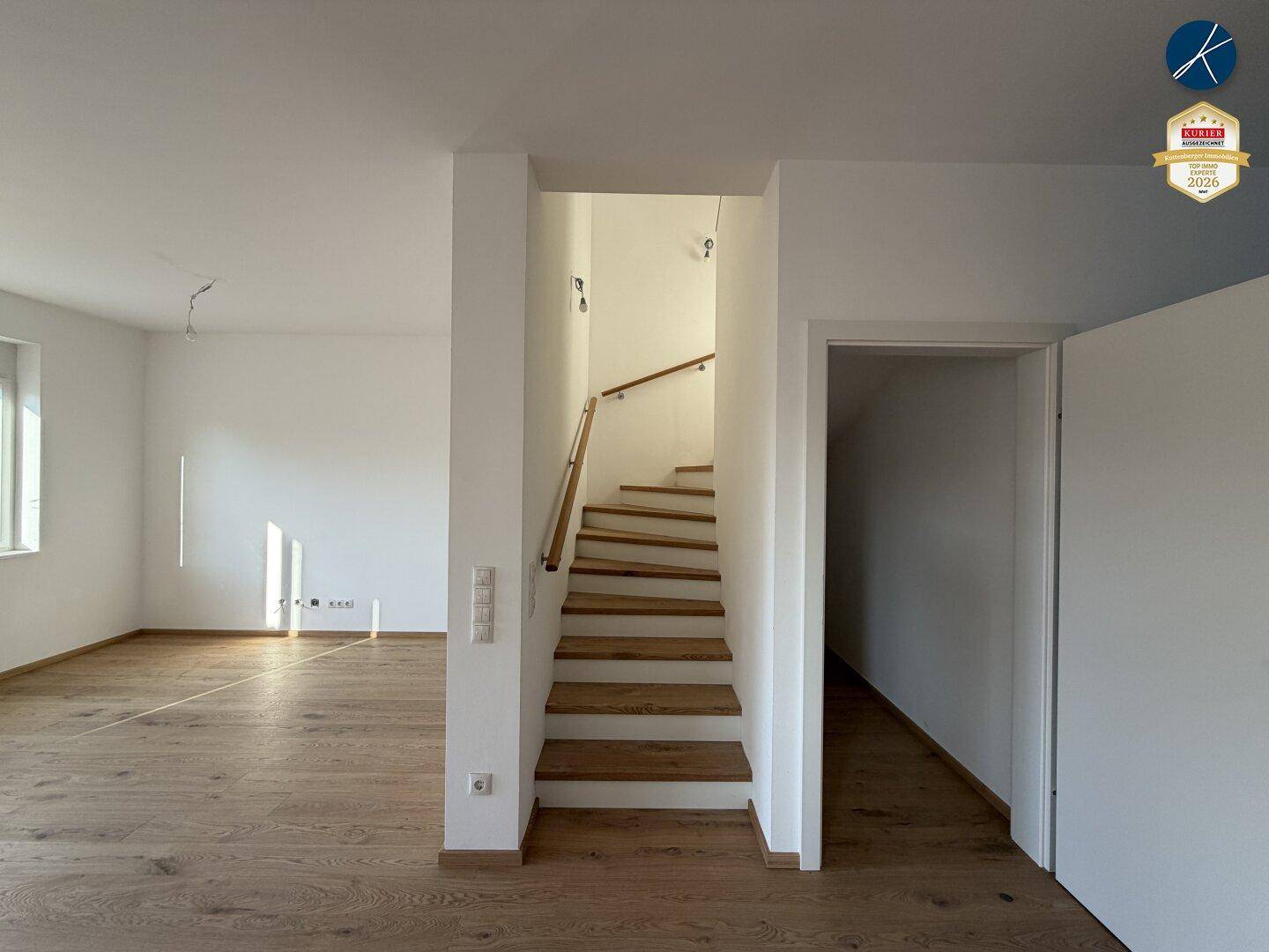 Heller Eingangsbereich mit Holztreppe, die in die oberen Stockwerke des Hauses führt.