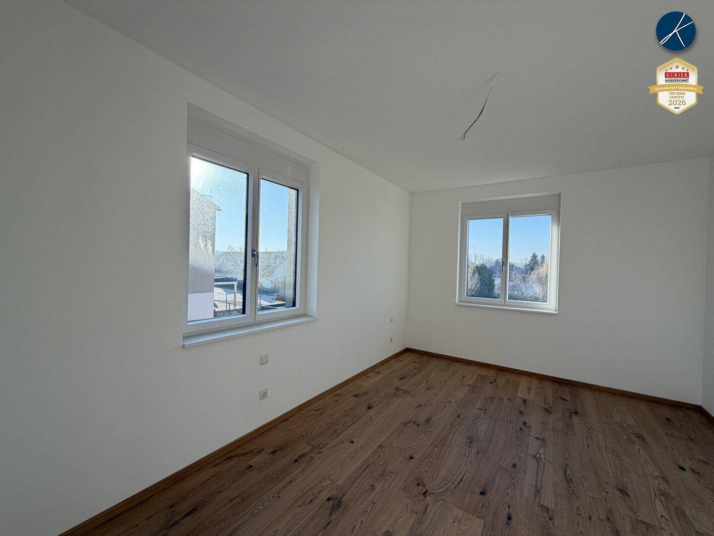 Helles Schlafzimmer mit Eichenparkettboden und großen Fenstern für viel Tageslicht.