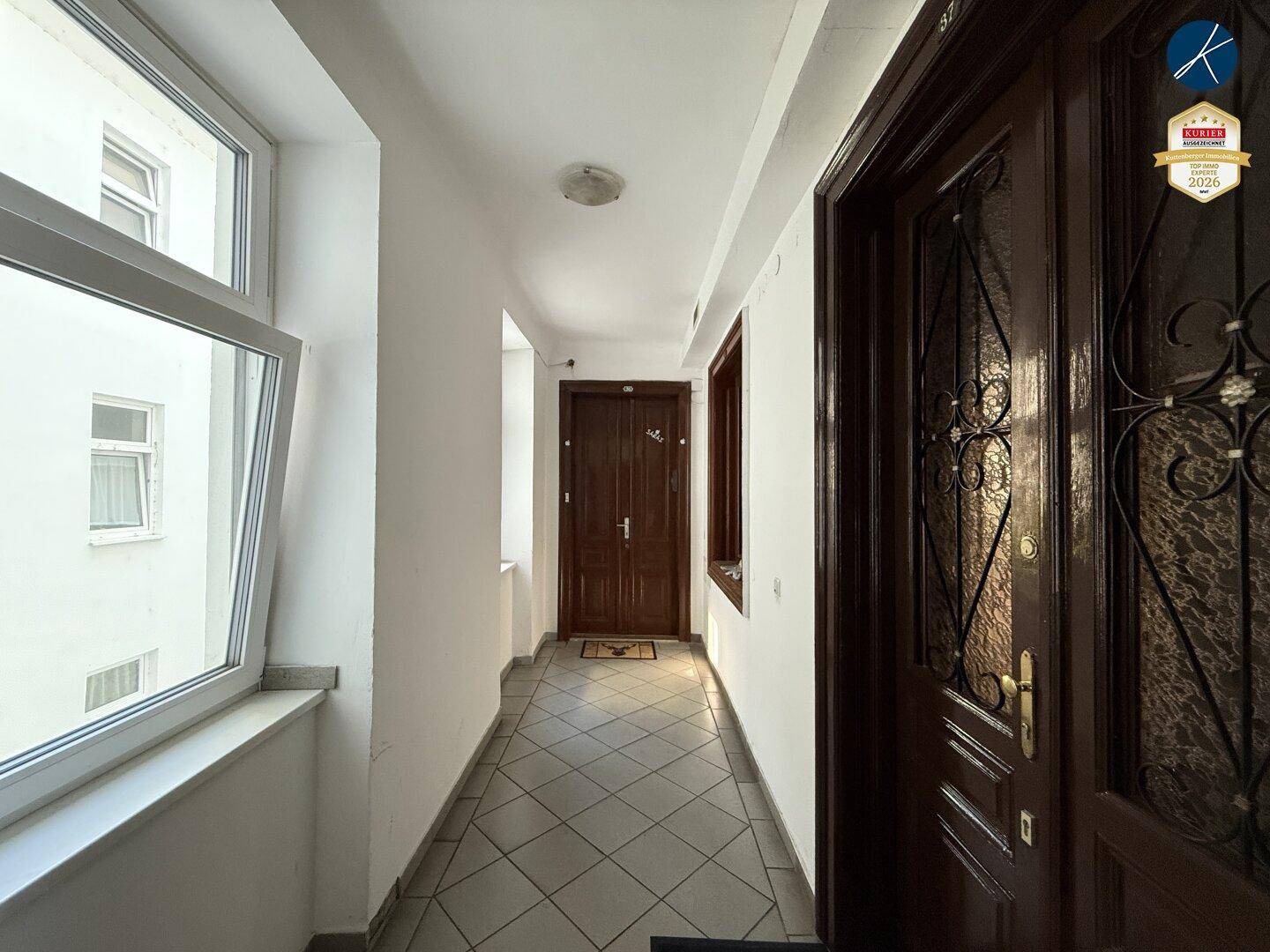 Heller Flur mit mehreren Wohnungstüren und Fenstern, die für natürliche Belichtung sorgen.