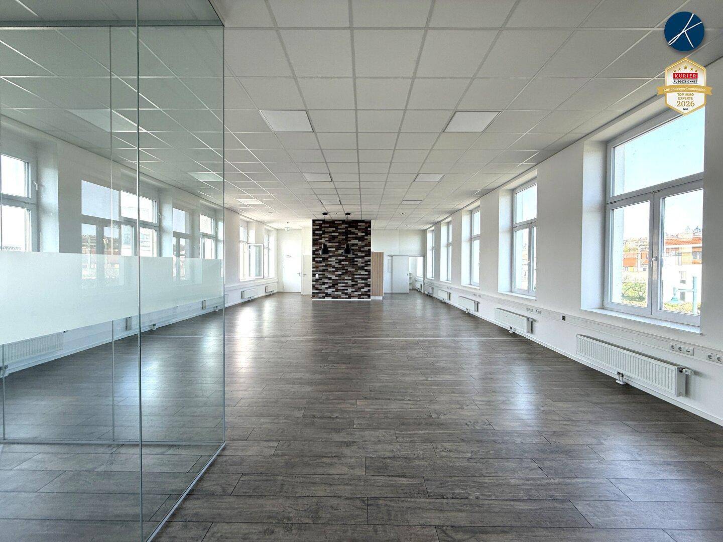 Helles, leeres Büro mit langen Fensterreihen und einer Akzentwand, ideal für flexible Bürolösungen.
