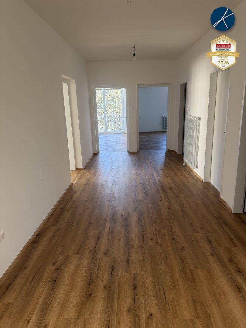 Heller Flur mit modernem Laminatboden, der zu weiteren Zimmern führt.