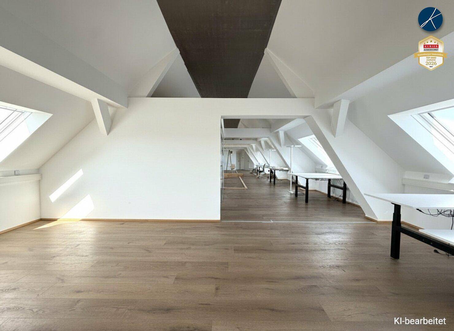 Weitläufiger offener Bürobereich im Dachgeschoss mit schrägen Wänden, Holzboden und moderner Einrichtung.