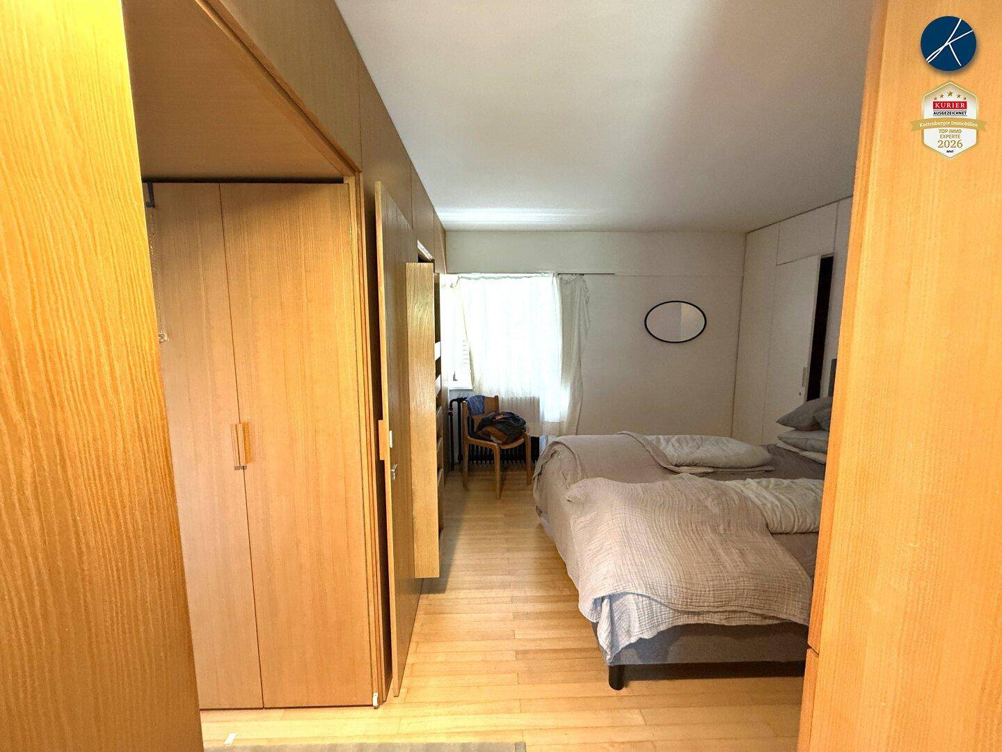 Gemütliches Schlafzimmer mit Holzboden, Doppelbett und maßgefertigten Holzschränken entlang der Wand.