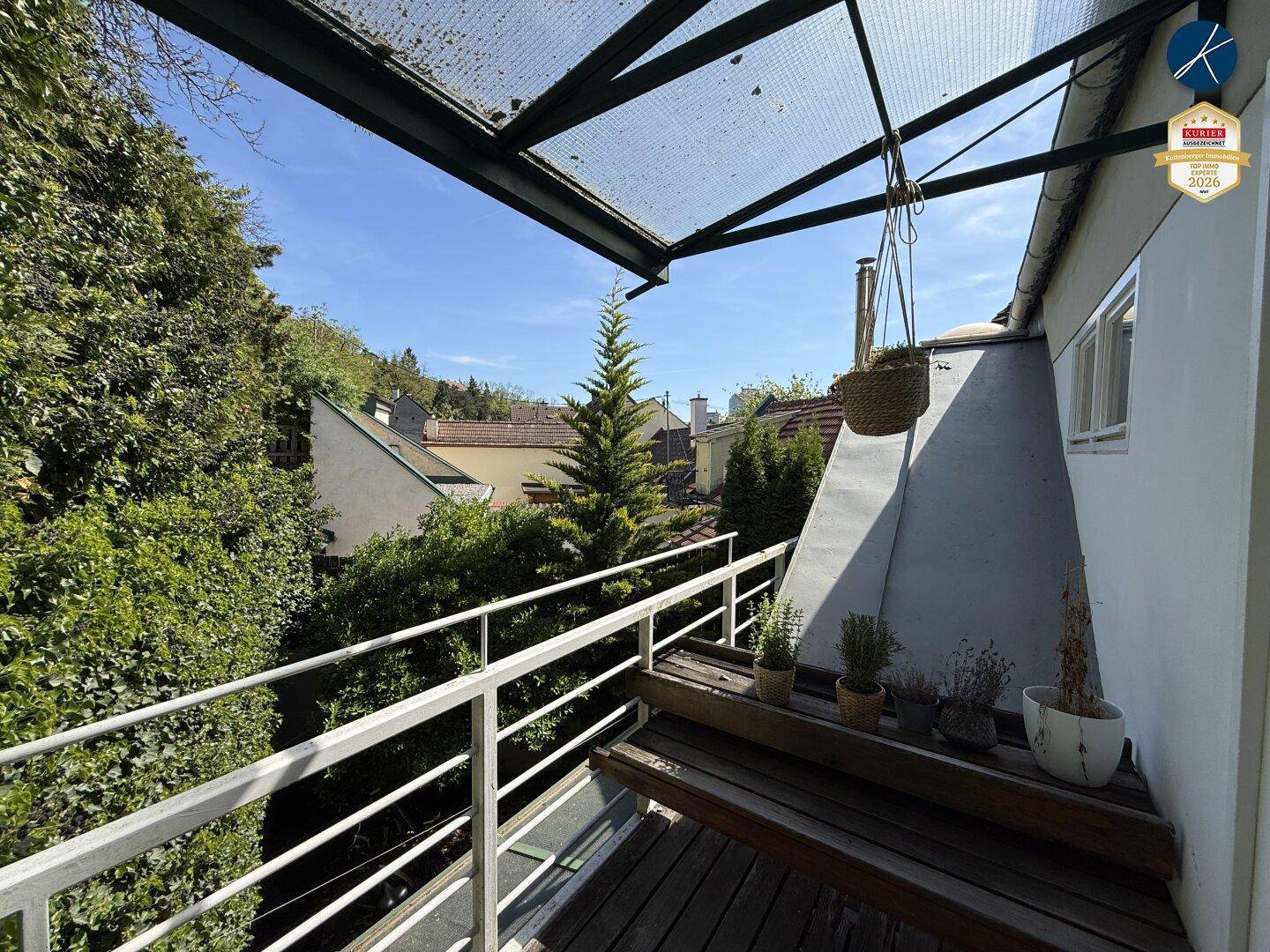Überdachter Balkon mit Metallgeländer und Ausblick auf die umliegende grüne Landschaft.