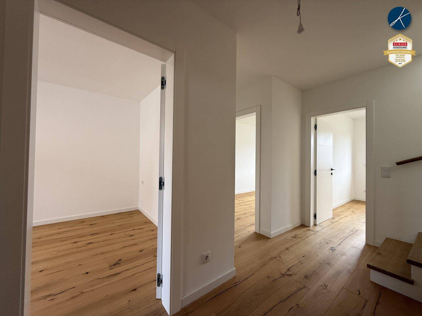 Heller Flur im Obergeschoss mit Holzboden und Zugang zu mehreren Zimmern.