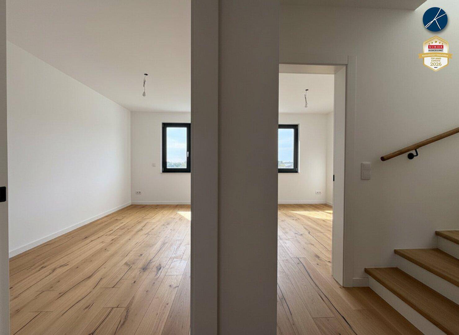 Obergeschoss-Flur mit Holzboden und Blick in zwei helle, leere Zimmer.