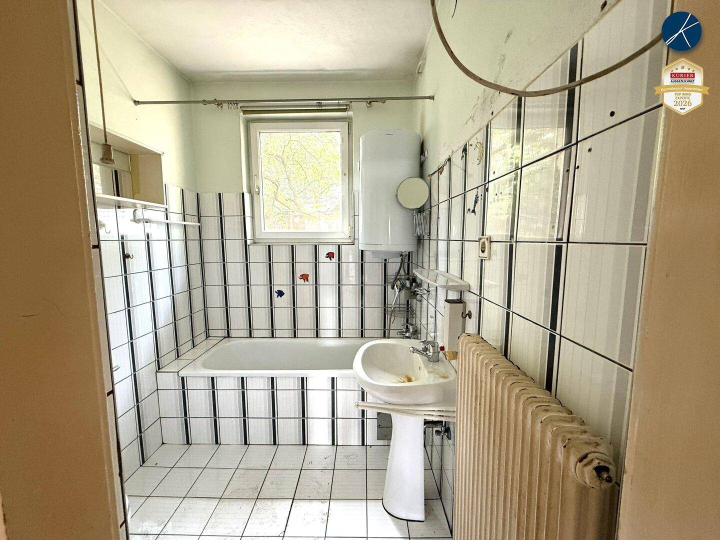 Badezimmer mit Badewanne, Waschbecken und Fliesen im Retro-Stil.