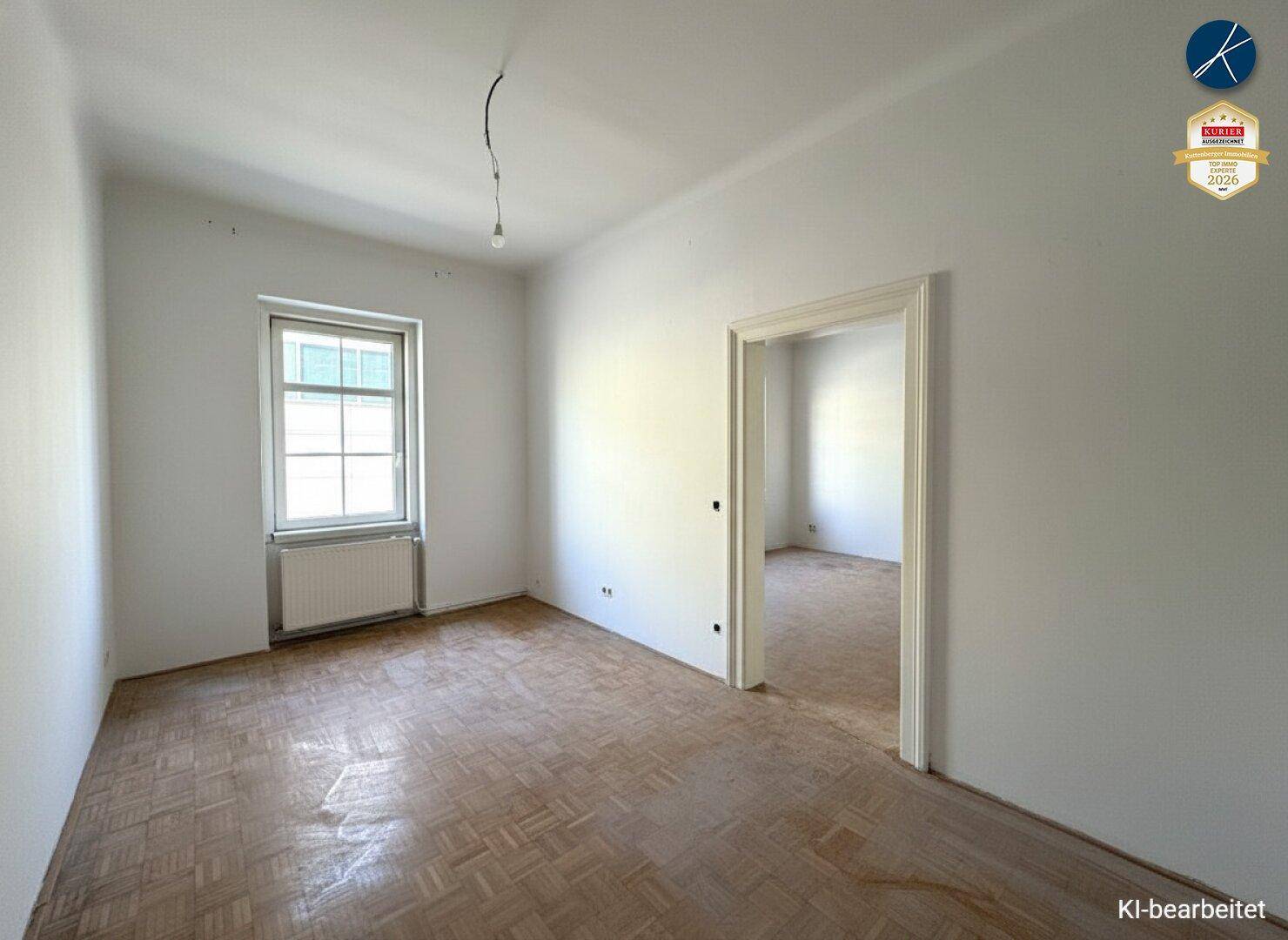 Geräumiges, helles Zimmer mit Parkettboden und Zugang zu einem weiteren Raum.