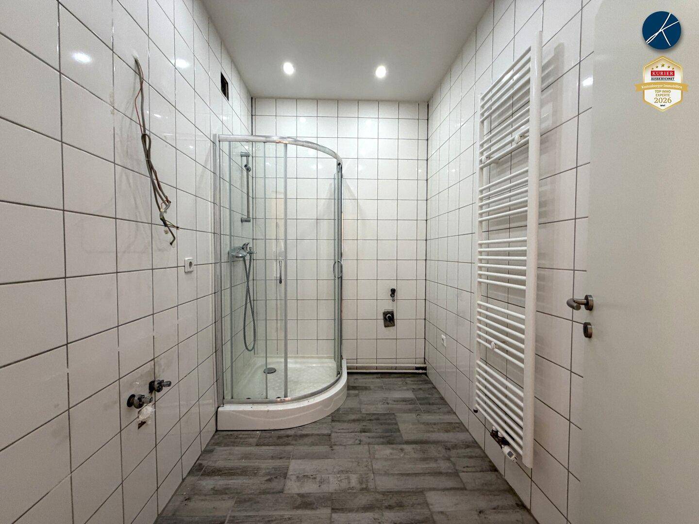 Modernes Badezimmer mit Duschkabine, weißen Fliesen und beheiztem Handtuchhalter.