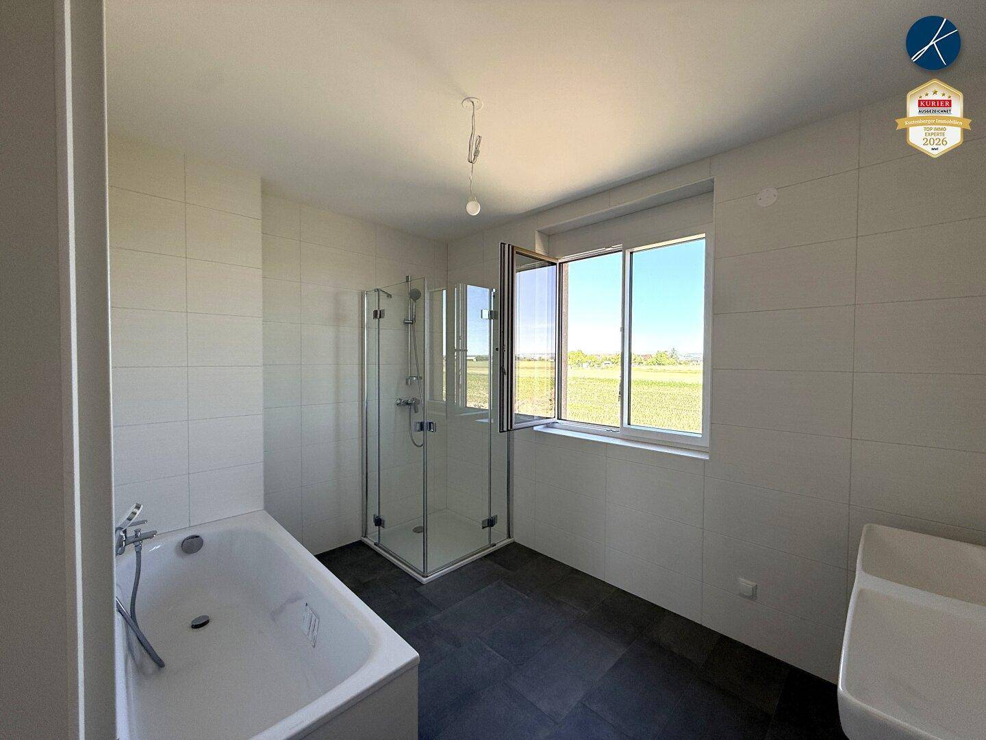 Modernes Badezimmer mit Badewanne, Duschkabine und Fenster mit weitem Ausblick.