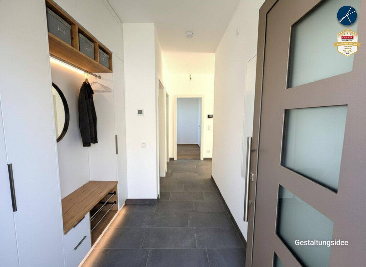 Heller Eingangsbereich mit dunklen Fliesen, Garderobe und modernem Design.