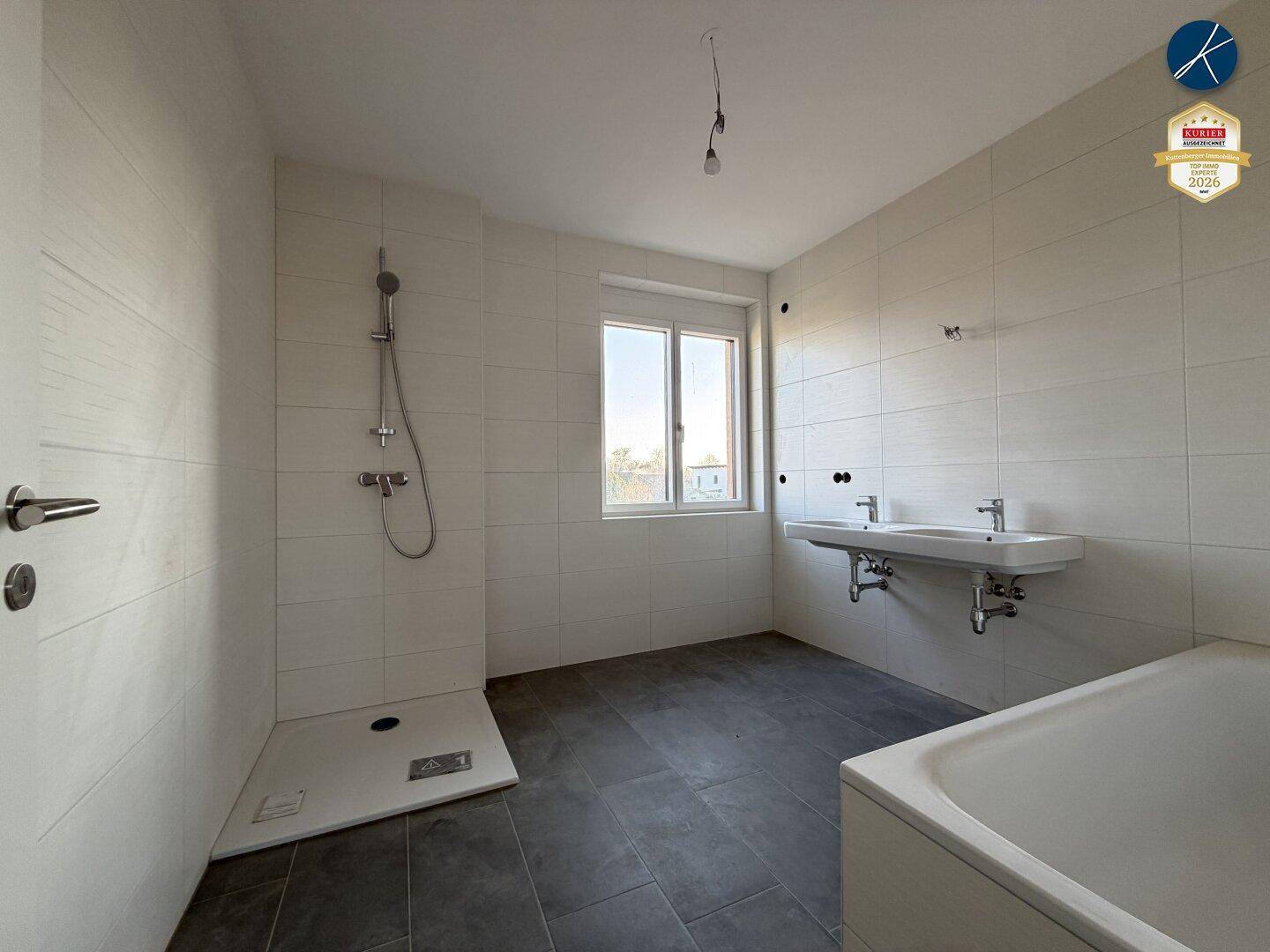 Modernes Badezimmer mit Dusche, Badewanne, Doppelwaschbecken und Fenster.