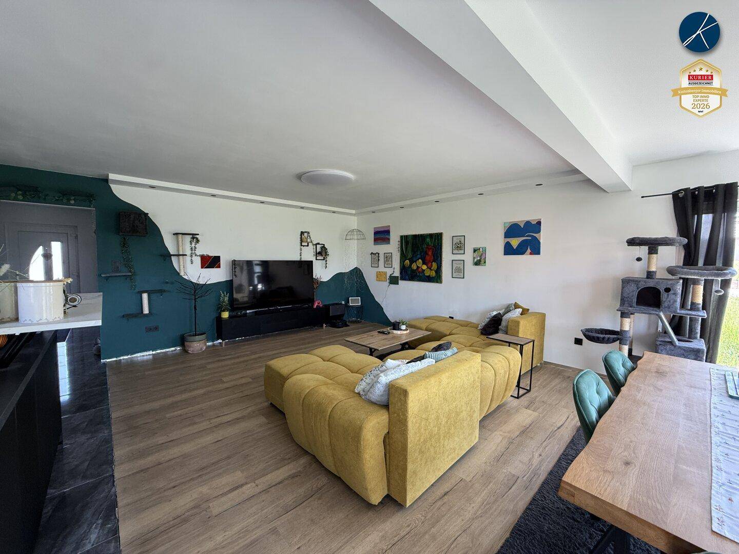 Geräumiger offener Wohn- und Essbereich mit großem Sofa und Holztisch, hell und modern gestaltet.