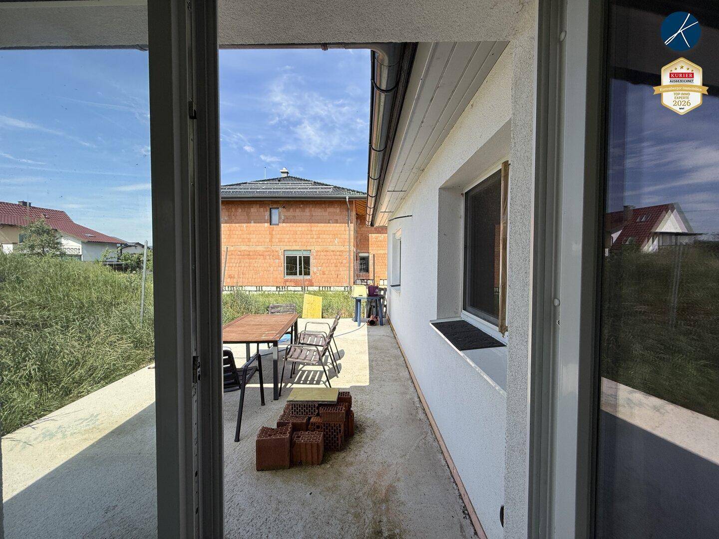 Seitliche Terrasse mit Gartentisch und Stühlen, ideal für entspannte Stunden im Freien.
