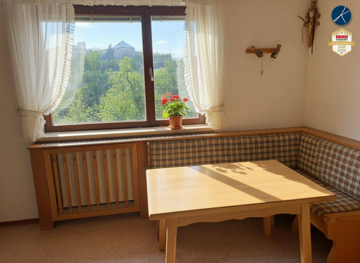 Gemütliche Essecke mit Holztisch, Eckbank und Fenster mit Blick ins Grüne, ideal für Mahlzeiten.