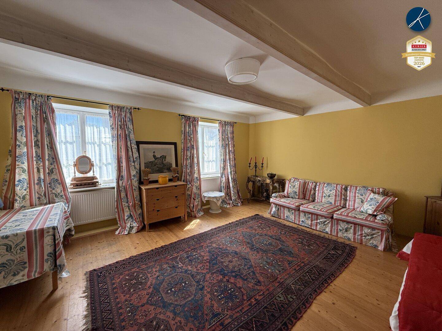 Helles Schlafzimmer mit Holzboden, gelben Wänden und sichtbaren Deckenbalken, traditionell eingerichtet.
