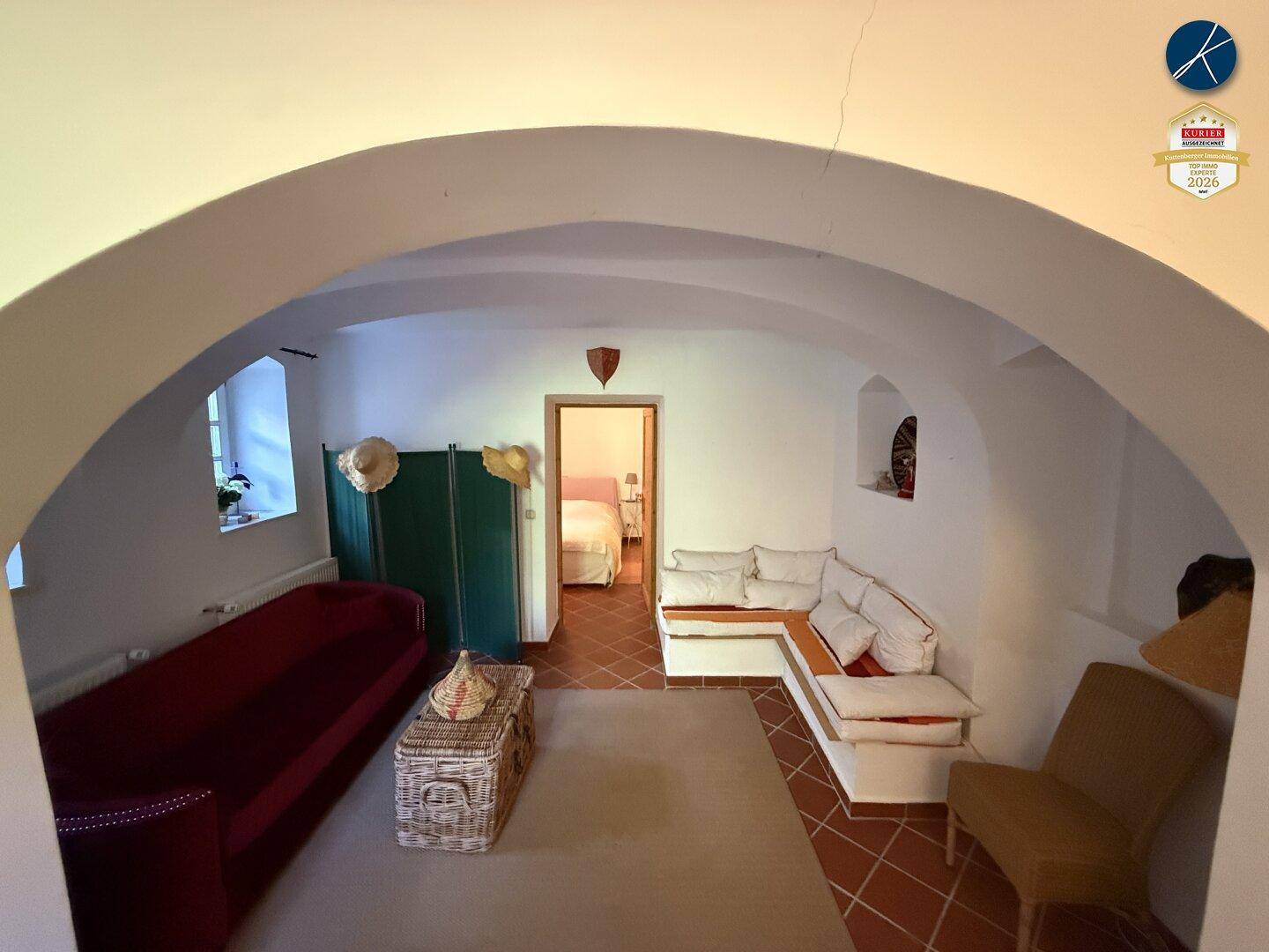 Gemütlicher Wohnbereich mit Gewölbedecke, Terrakotta-Fliesenboden und eingebauten Sitzgelegenheiten.