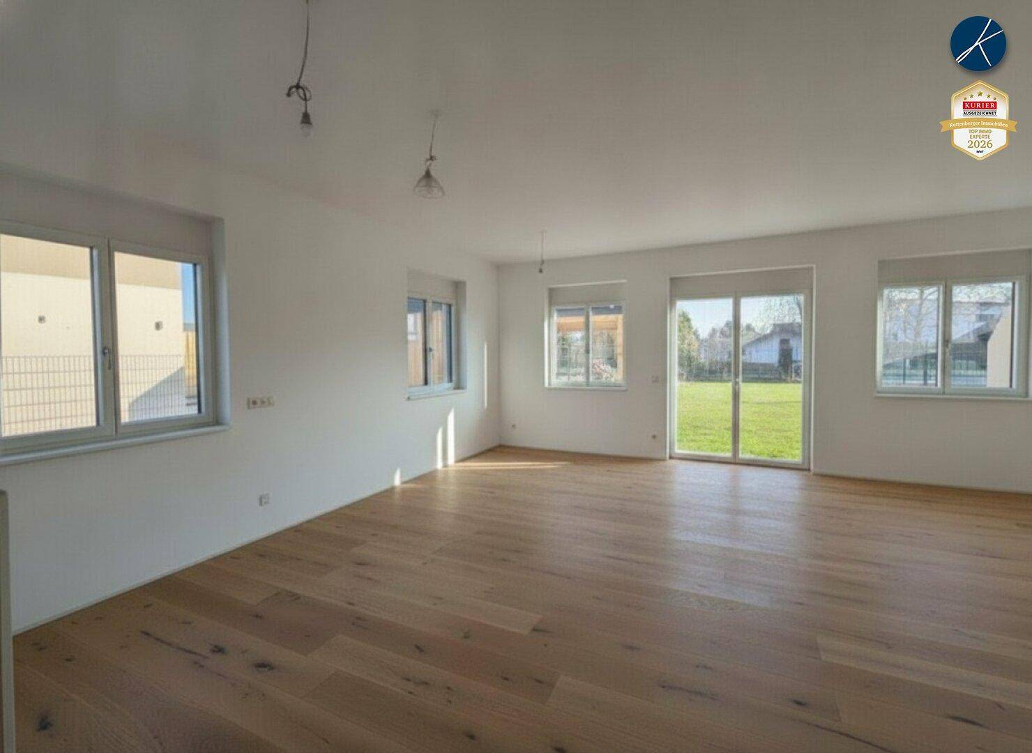 Helles Wohnzimmer mit Holzboden und großem Zugang zum Gartenbereich.